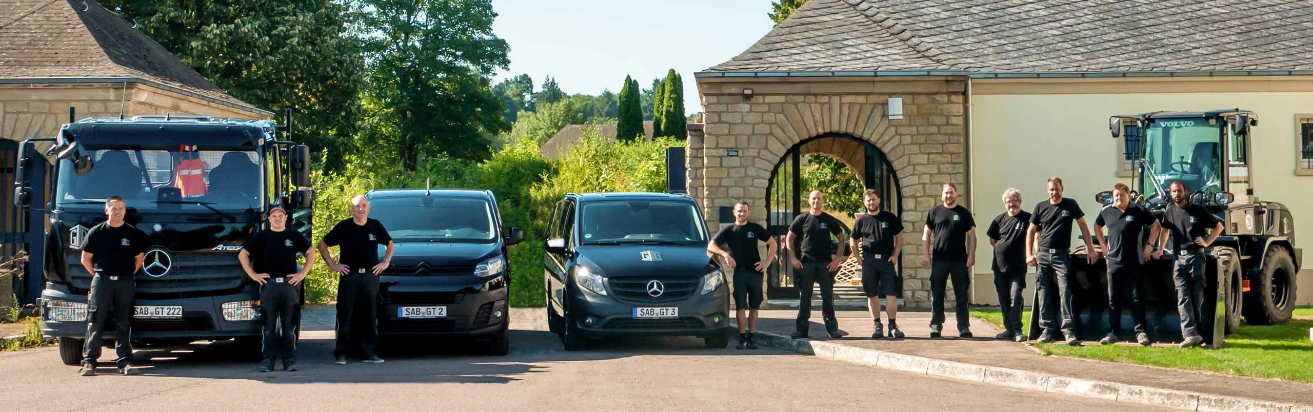 Das Team von GT Bau vor Firmenfahrzeugen und Baumaschinen in Saarburg